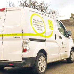 Image showing the rear quarter of our Print Services Electric Delivery van displaying the liveried side graphics of a lime green plug to illustrate the environmental impact